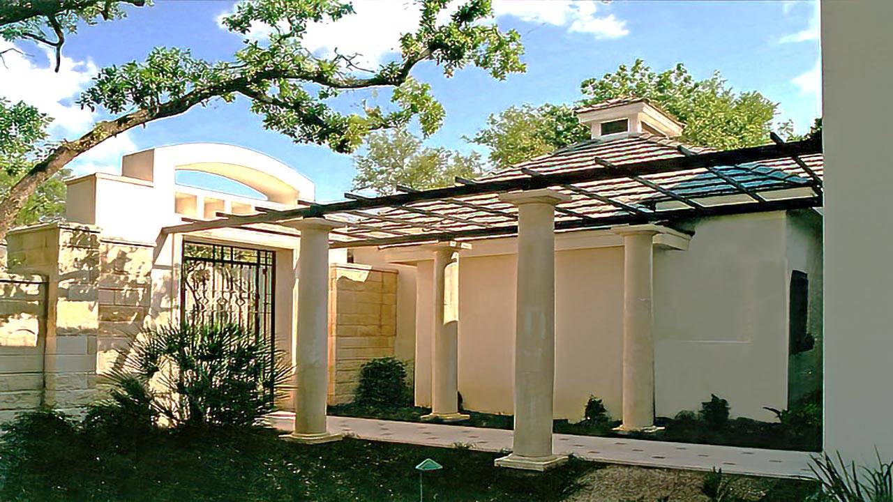 Modern house with cut stone columns, metal trellis, at entry courtyard